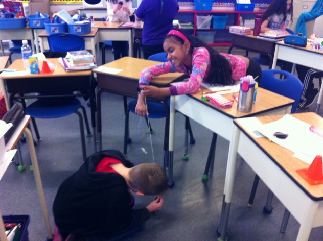 Two Grade 4 students working hard to set up their fixed pulley. 